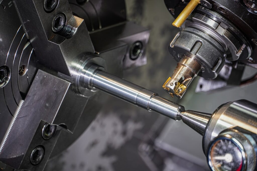 A person in safety glasses carefully aligns a metal workpiece in a CNC milling machine using a dial indicator.