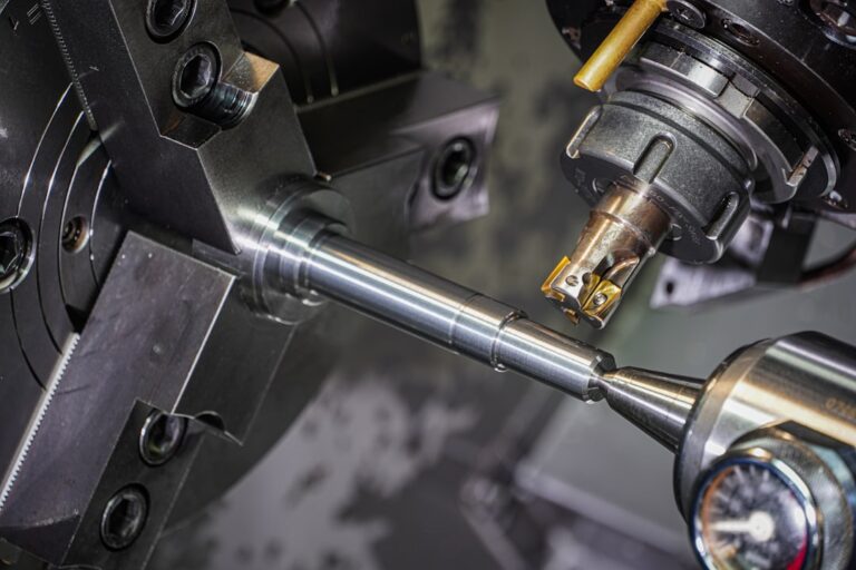 A person in safety glasses carefully aligns a metal workpiece in a CNC milling machine using a dial indicator.