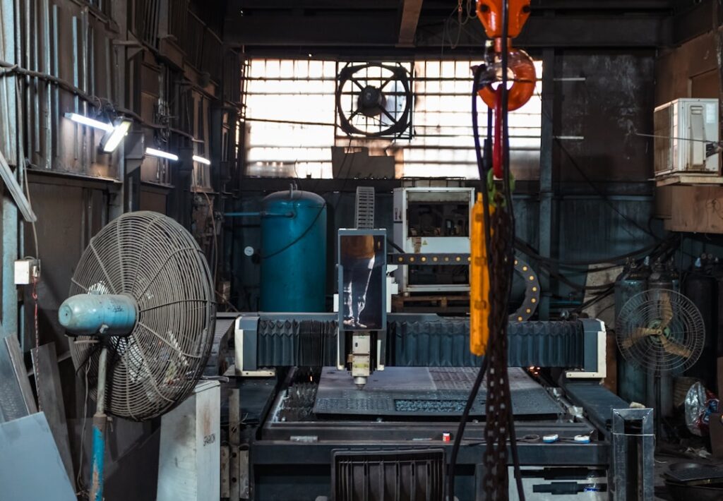 Machinist inspecting a precisely machined metal part under bright workshop lighting.
