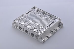 A person inspecting a machined metal part for surface texture under bright lighting.