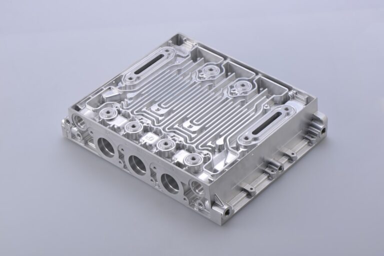 A person inspecting a machined metal part for surface texture under bright lighting.