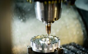 Operator reviews a 3D CAD model beside a CNC machine with cutting tools and metal stock.
