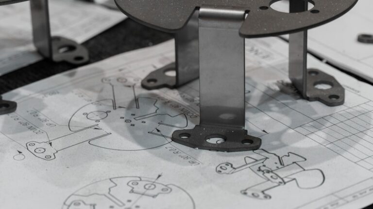 A person reviewing a technical drawing next to a CNC-machined metal part on a clean workbench.